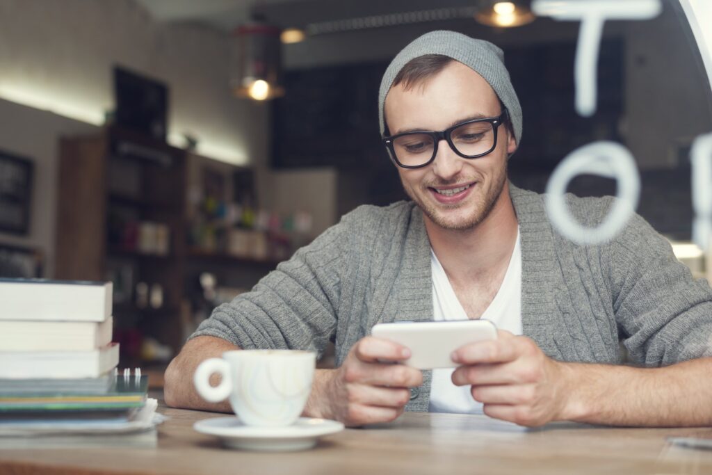 millennial man looking at phone in coffee shop
