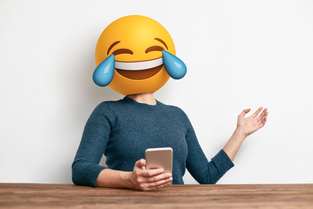 Woman with emoji as head laughing on her phone