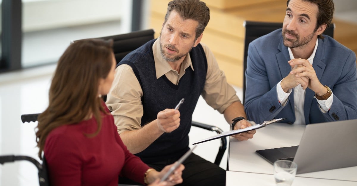 Three colleagues reviewing figures together over a laptop in an office