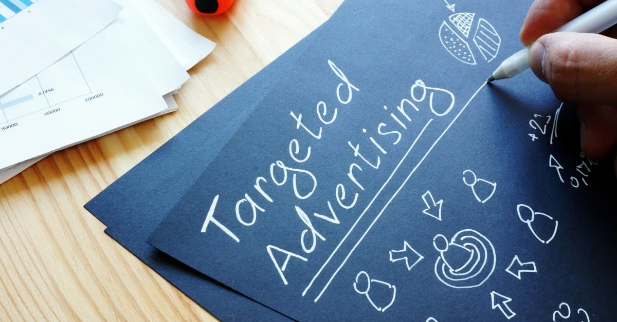 The words Targeted Advertising handwritten on dark paper beside printed charts