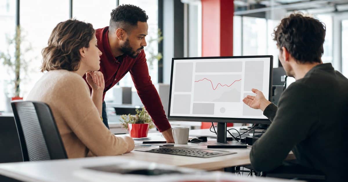 Three colleagues reviewing a marketing performance dashboard together in an office