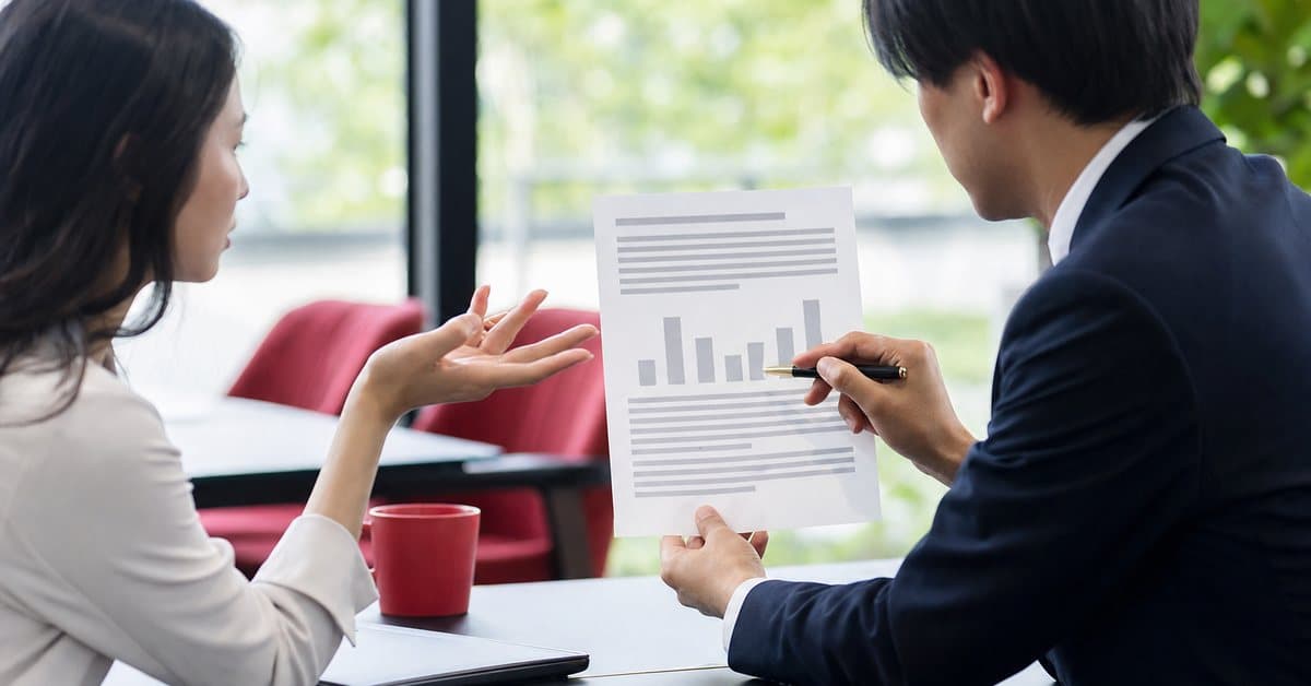 A business owner questioning an agency about a printed proposal in a meeting